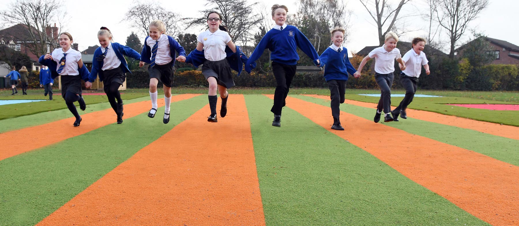 Children holding hands and playing on LazyLawn artificial grass